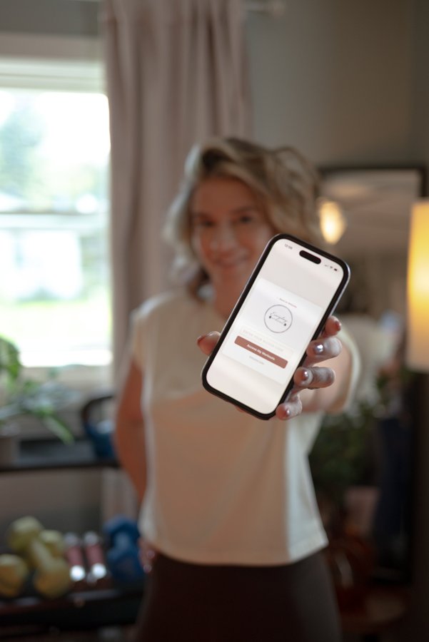Heather holding a phone showing the Everyday Strong app